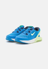 Chaussures de sport bleues avec une tige en maille, une semelle intermédiaire blanche, des accents verts et un design de talon unique pour un amorti et un soutien.