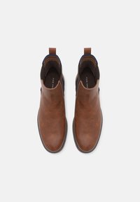 Brązowe skórzane botki za kostkę o gładkiej fakturze, z elastycznymi panelami bocznymi i pętlami do zakupu. Czarne gumowe podeszwy, minimalne detale szwu.