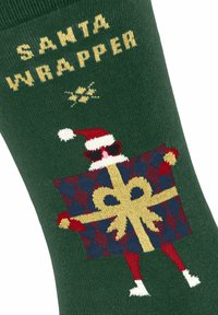 Grüne Socken mit dem Text "SANTA WRAPPER", verziert mit einem bunten Design eines Weihnachtsmanns, der ein Geschenk hält, und roten sowie weißen Akzenten.