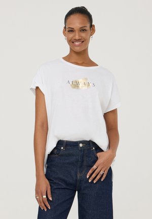 T-shirt bianco con vestibilità ampia e maniche arrotolate, caratterizzato dalla stampa in foglia d'oro "ALWAYS" sul davanti, abbinato a jeans in denim scuro.