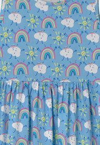 Niebieska bawełniana sukienka z wesołym wzorem uśmiechniętych chmurek, tęczy i słońc. Spódnica ma marszczony fason, który dodaje objętości.