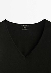 Encolure en V noire d'un vêtement avec étiquette de marque Massimo Dutti et étiquettes de taille visibles à l'arrière, fabriqué en Chine.