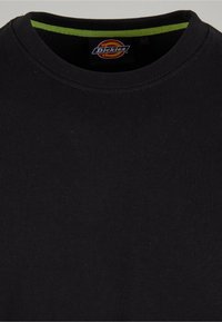 Mustat lyhythihainen t-paita, joka on valmistettu puuvillasta, pyöreällä kaula-aukolla. Paidassa on kontrastivihreä sisäkaulus ja Dickies-logo-etiketti.