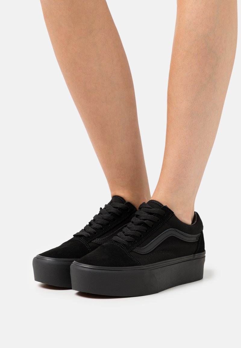 Sorte ruskinds sneakers med en platformsål, der har et fladt snørebåndsdesign og en sidelinje i en lignende sort nuance.