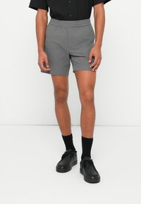 Gray shorts with textured fabric, elastic waistband, and a relaxed fit. Paired with black socks and black shoes.