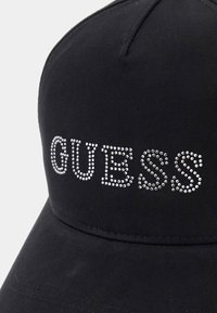 Cappellino da baseball nero con tessuto a trama, con la parola "GUESS" in strass sulla parte anteriore. Visiera curved e dettagli cuciti.