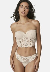 Corset sans bretelles en dentelle nude avec motif floral, bords festonnés et découpes décoratives ; accompagné d'un string en dentelle assorti.