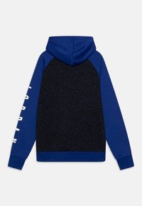 Bluza z kapturem z niebieskim przodem pokrytym rozproszonymi ciemnymi plamkami na plecach, niebieskimi rękawami raglanowymi oraz białym logo na rękawie.