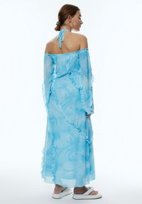 Lichtblauwe off-the-shoulder jurk met gerimpelde mouwen en zoom, voorzien van een gemarmerd patroon en een striksluiting aan de achterkant.
