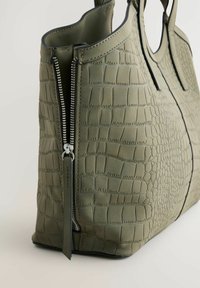 Olivengrøn totebag i fake læder med krokodilleskindsstruktur, der har en sølvfarvet lynlås og dobbelte håndtag for nem transport.
