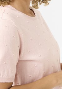 Jasnoróżowy sweter z dzianiny z krótkimi rękawami, z teksturowanymi detalami w kształcie bobli oraz prążkowanym dekoltem i mankietami.