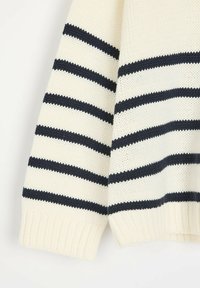 Sweter z dzianiny w kremowej podstawie i granatowych paskach. Posiada ściągacze przy mankietach i u dołu. Wykonany z miękkiej, teksturowanej przędzy.
