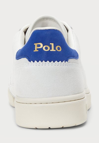 Vit mockasnöre med en blå hälflik som har "Polo" i guld. Rundad form, texturerad yta och en krämfärgad gummisula.