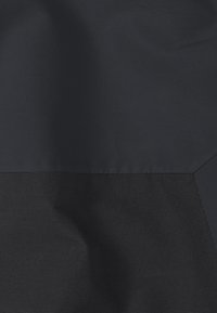 Marineblauer Stoff mit einer glatten Textur und einem kontrastierenden matten Abschnitt darunter; entworfen in einer einfachen, nahtlosen Form ohne sichtbare Beschläge.