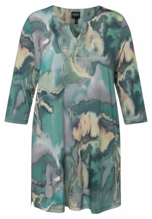 Langærmet tunika i blød, flydende stof med et teal- og gråspraglet mønster. Har en V-halsudskæring og sideslider for nem bevægelse.