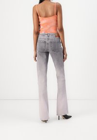 Šedé džíny s rozšířenými nohavicemi a jemným přechodem barvy, s pěti kapsami a zadními záplatami. Kombinovány s těsně padnoucím oranžovým topem a černými botami na podpatku.