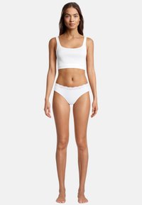 Weißes Baumwoll-Crop-Top und passende weiße Panties mit Spitzenbesatz. Schlichtes Design, weiche Textur und figurbetonte Form.