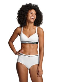 Bralette blanca con banda de logo negra de Puma y tirantes ajustables, combinado con bragas blancas de tiro alto a juego con banda de logo.