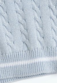 Tissu tricoté bleu clair avec un motif en relief et un bord côtelé, présentant une fine rayure horizontale blanche.