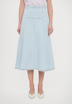 Fustă midi din denim albastru deschis, cu o croială evazată, cusături vizibile și două buzunare la spate. Asortată cu pantofi albi cu vârful ascuțit.