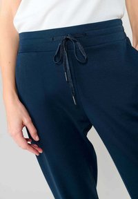 Joggers de color azul marino hechos de tela suave, con cinturilla elástica, cierre con cordón y bolsillos laterales, que presentan una textura lisa.
