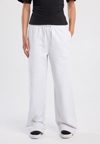 Vaaleanharmaat collegehousut, jotka on valmistettu pehmeästä kankaasta. Niissä on nyöri vyötäröllä, leveät lahkeet ja sivutaskut. Koristeena on huomaamaton logo reidessä.