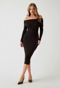 Robe midi noire côtelée avec manches épaules dénudées et détails de boutons sur le côté. Présente une silhouette ajustée et une texture lisse.