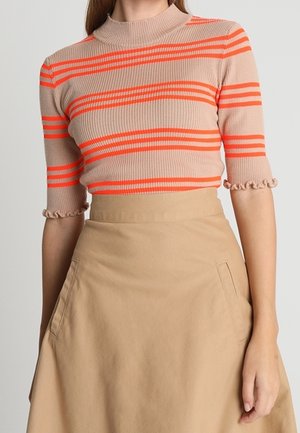 Haut à manches courtes côtelé beige avec des rayures horizontales orange vif ; il présente un col haut et des ourlets de manches froncés. Associé à une jupe beige.