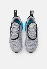 Zapatillas deportivas grises con una parte superior de malla transpirable, acentos negros, una suela azul brillante y una cinta de agarre pronunciada en el talón.