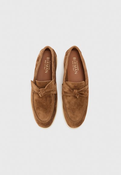 Brūni zamši loafers ar banti, apaļu purngalu un kontrastējošu beigu gumijas zoli. Zīmola iekšējais zole lasāms "ALEXANDRE BIRMAN, MADE IN ITALY."