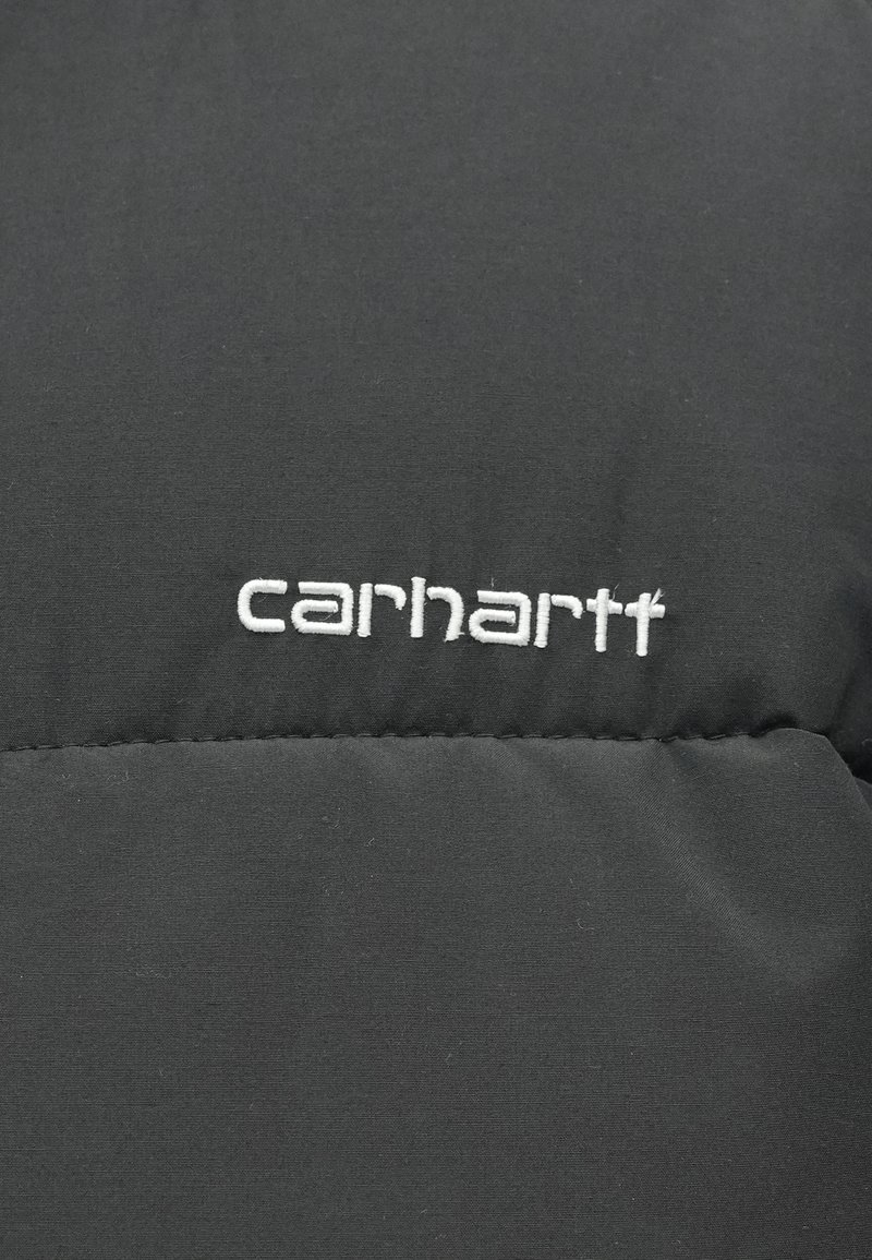 Giacca nera isolata con tessuto liscio e opaco e motivi cuciti, con logo "carhartt" ricamato in bianco.