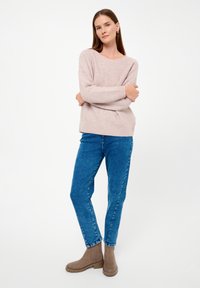 Light pink knitted sweater with horizontal stripes, paired with blue denim jeans and brown ankle boots. Relaxed fit, minimal details.