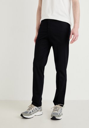 Black pants made of smooth fabric, featuring a straight-leg design. Paired with gray athletic shoes with mesh detailing and laces.