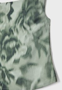 Ärmlös topp i ett mjukt, strukturerat tyg med ett bleknat grönt blommönster. Designen inkluderar en rundad nederkant och minimala sömnadsdetaljer.