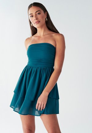 Teal strapless dress with layered skirt, made of lightweight fabric. Features a fitted bodice with gathering and soft flowy texture.