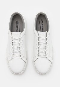 White low-top sneakers with a smooth leather upper, round toe, and flat laces. Interior features a textured gray lining and logo beneath laces.