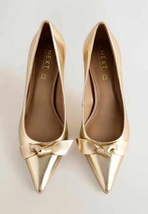 Goldene spitze High Heels mit einer flachen Schleifen-Akzent an der Vorderseite. Glatte metallische Oberfläche an der Oberseite und eine gepolsterte Innensohle für Komfort.