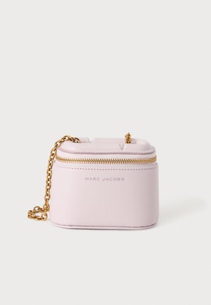 Μικρή ανοιχτό ροζ δερμάτινη τσάντα Marc Jacobs με χρυσή αλυσίδα και χρυστό φερμουάρ στο πάνω μέρος πάνω σε λευκό φόντο.