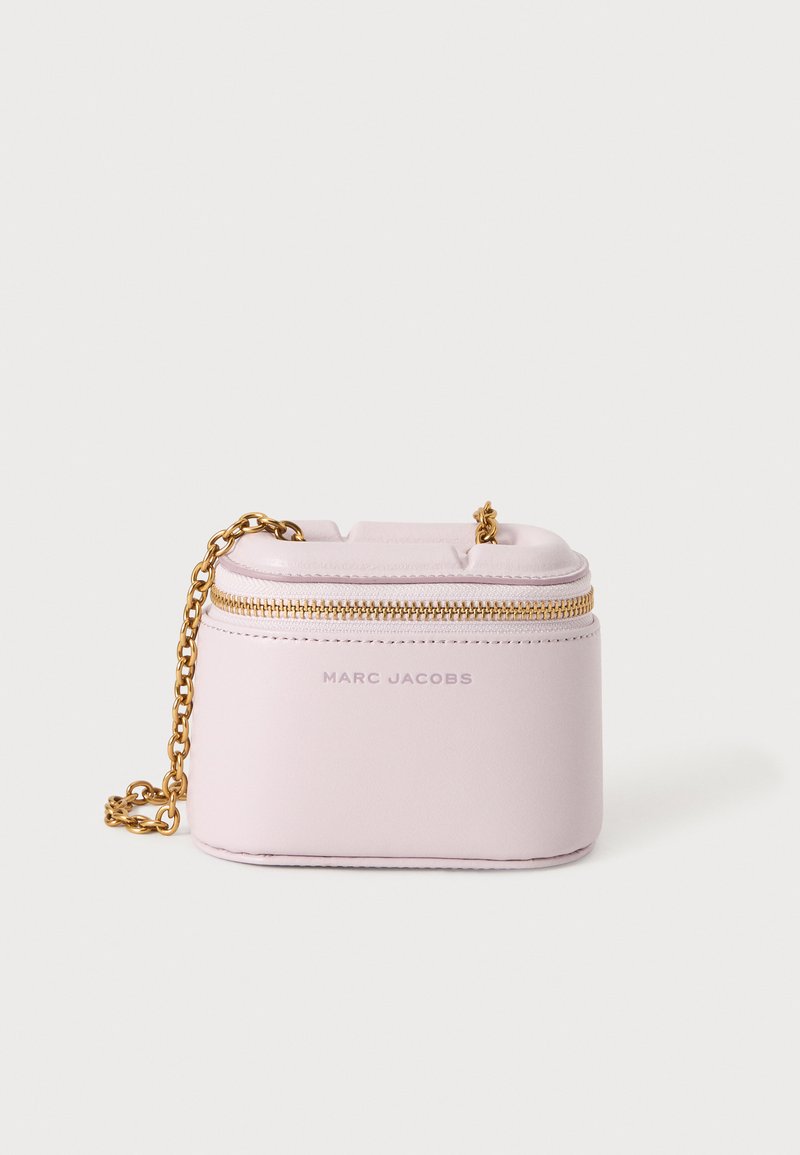 Μικρή ανοιχτό ροζ δερμάτινη τσάντα Marc Jacobs με χρυσή αλυσίδα και χρυστό φερμουάρ στο πάνω μέρος πάνω σε λευκό φόντο.