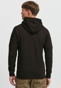 Schwarzer Kapuzenpullover mit lockerer Passform, ausgestattet mit einer Kordelzugkapuze, langen Ärmeln und gerippten Bündchen. Glatte Textur mit minimaler Ausstattung.