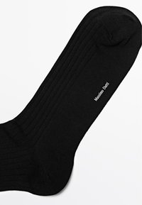 Calza nera a costine realizzata in tessuto strutturato. Presenta una punta arrotondata e il nome del marchio "Massimo Dutti" stampato in bianco sul lato.