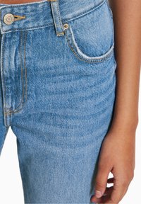 Jeans in denim azzurro chiaro con vita alta, caratterizzati da cuciture arancioni, una tasca frontale e un bottone in metallo in vita.