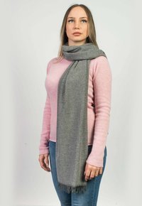 Grå scarf av mjukt material med fransade ändar. Stiligt avslappnat över en ljusrosa tröja. Enkel, rektangulär design.