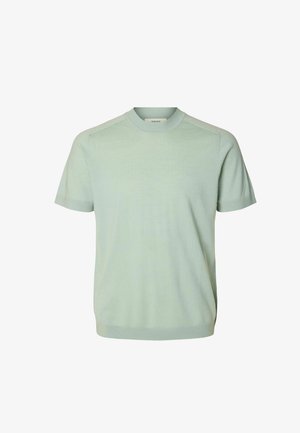 Hele roheline lühikeste varrukatega kootud kampsun soonikkoes ümarkaeluse, varrukaäärte ja äärega, valgel taustal.