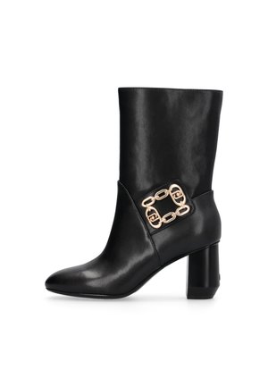 Stivaletto in pelle nera con punta affusolata, tacco spesso e una catena dorata decorativa sul lato. Texture liscia e design elegante.