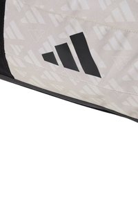 Borsa Adidas in tessuto grigio chiaro testurizzato con un motivo geometrico nero e logo. Include dettagli neri e una finitura liscia.