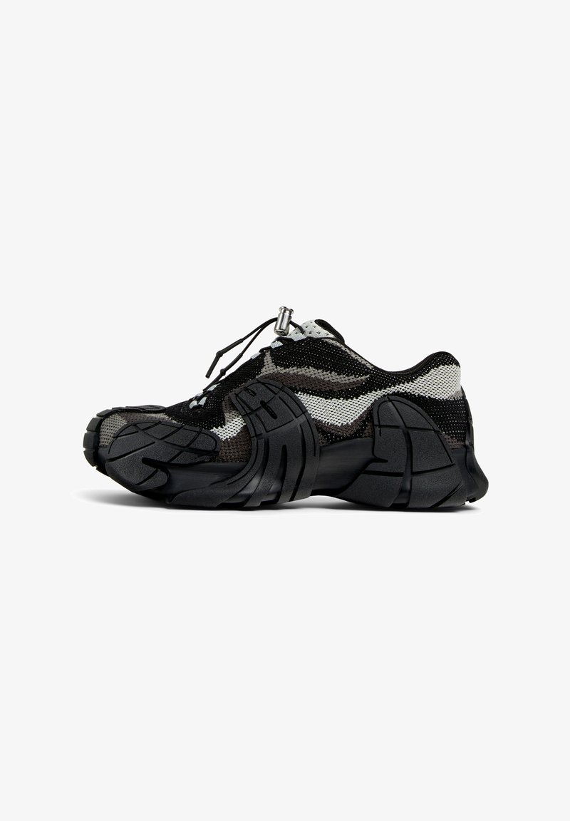 Zwart-witte sneakers van mesh en rubber. Voorzien van een ronde neus, dikke, gerenommeerde zool en stevig met een toggle-schoenenrand.