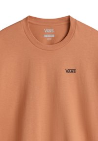 T-shirt a maniche corte in cotone color arancio chiaro con colletto a girocollo e un piccolo logo Vans nero sul petto. Morbido al tatto, design casual.