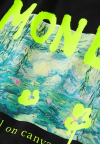 Černá tkanina s živou zelenou textovkou "MONET" nad barevným obrazem leknínu od Moneta. Hladká textura a výrazný barevný kontrast.