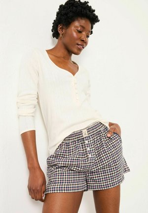 White ribbed long-sleeve top with a V-neck and five buttons, paired with blue and cream checkered shorts featuring an elastic waistband.